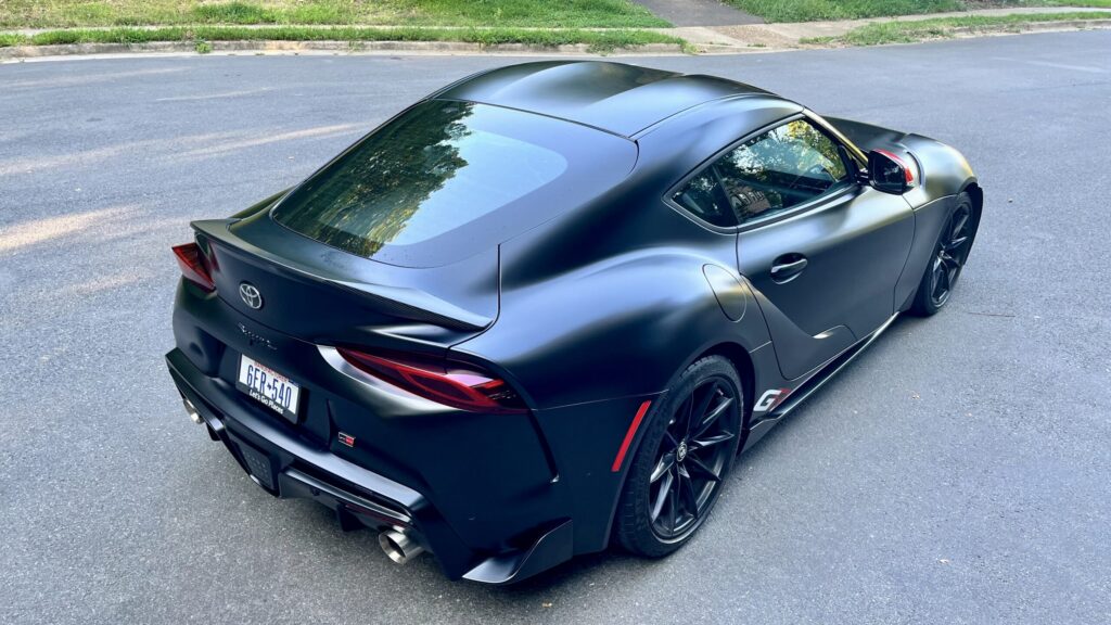 Dark gray 2026 Toyota GR Supra MkV Final Edition rear three-quarter view with ducktail spoiler and twin exhaust outlets
